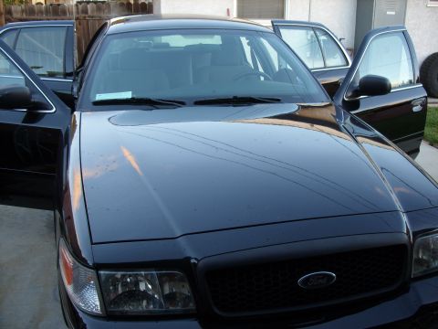 2005 Ford Crown Victoria - A black sedan, possibly a 2005 Ford Crown Victoria, is parked with its doors open, showing its interior.