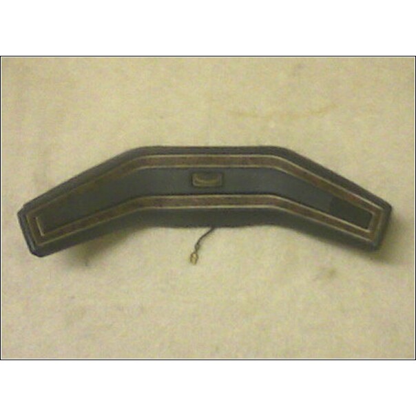Dark dashboard trim piece with gold accents and a wire