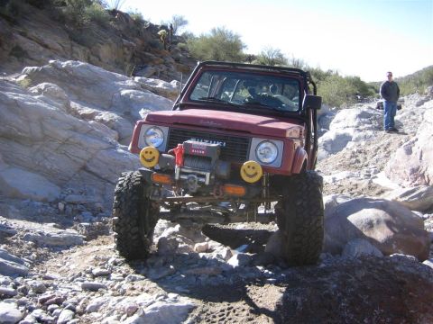 1987 Suzuki Samurai - Suzuki Samurai tackling a challenging rocky off-road course with a winch mounted on the front bumper.