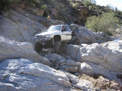 1987 Suzuki Samurai - This heavily modified 1984 Toyota pickup truck navigates a challenging rocky trail, its off-road capabilities.