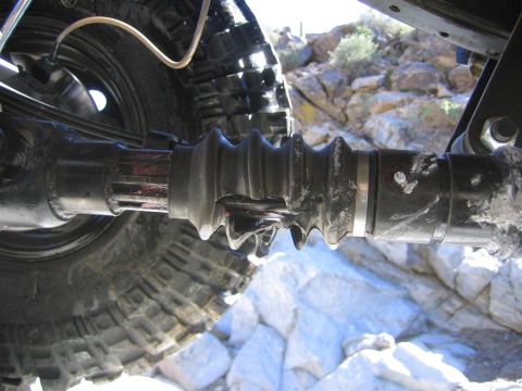 1987 Suzuki Samurai - A close-up view of a damaged driveshaft boot on a vehicle's wheel assembly, with a Supermotors.net logo in the corner.