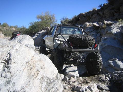 1987 Suzuki Samurai - Modified off-road truck navigates a challenging rocky terrain, with another vehicle visible in the background.