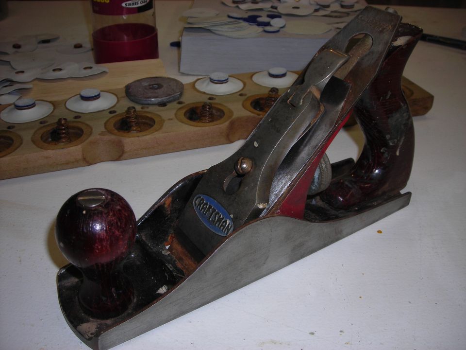 Craftsman hand plane on a workbench with a wooden organizer holding small parts