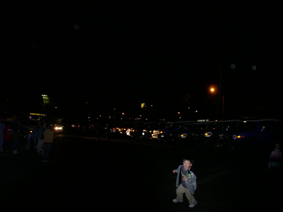 Boy in foreground, vehicles in background at night