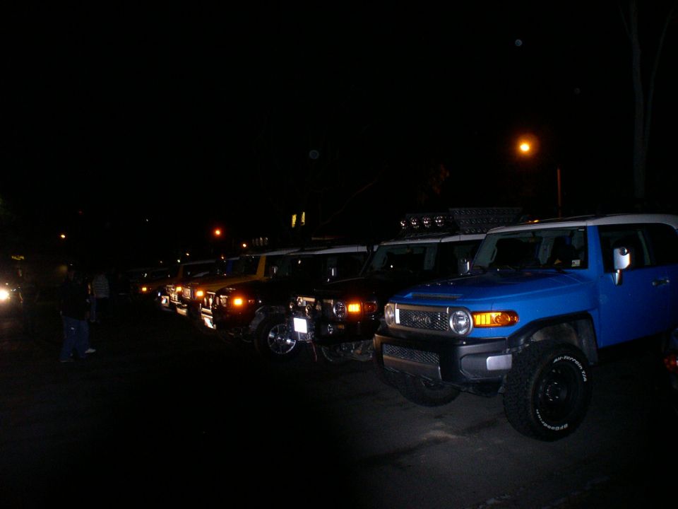 Blue 2007 Toyota FJ Cruiser in foreground, with other FJ Cruisers lined up behind it at night