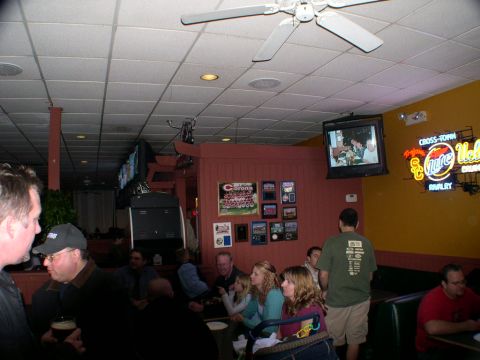 2007 Toyota FJ Cruiser - People gather inside a dimly lit establishment with multiple televisions and neon signage visible.