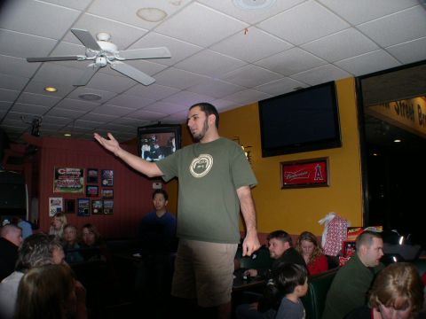2007 Toyota FJ Cruiser - A group of people are seated in a dimly lit establishment while a man stands and gestures.