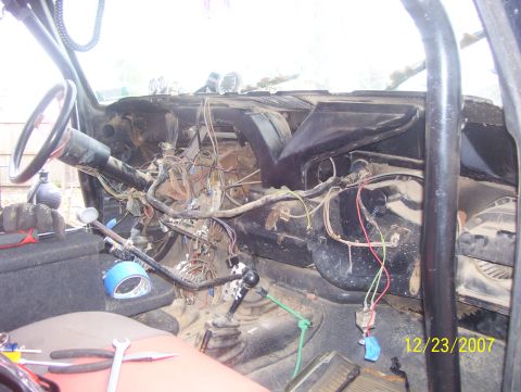1978 Ford Bronco - Dashboard wiring and roll cage visible in a 1978 Ford Bronco interior. Tools are present on the seat.