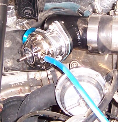 1988 Pontiac Fiero - Close-up of a chrome blow-off valve with a blue hose attached to black piping.