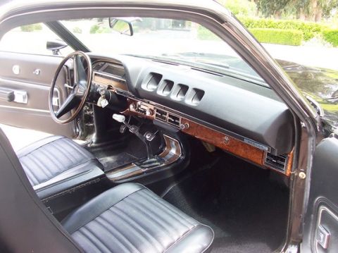 1972 Ford Ranchero - The interior of a classic car features a wood-grain dashboard and black vinyl seats.
