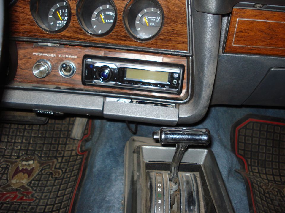 Woodgrain dash with aftermarket CD stereo, gauges, and floor automatic shifter