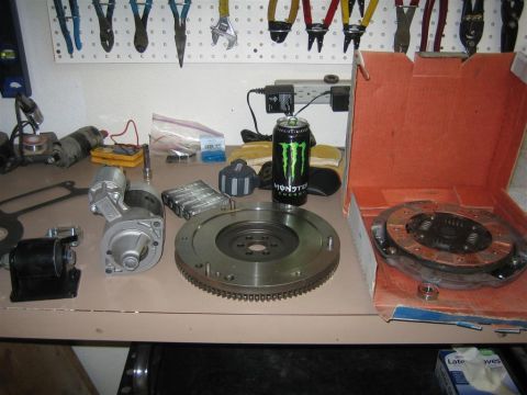 1987 Suzuki Samurai - A clutch kit, flywheel, and starter motor are laid out on a workbench, alongside a Monster Energy drink.