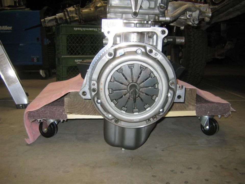 Engine clutch assembly resting on a wooden dolly with casters