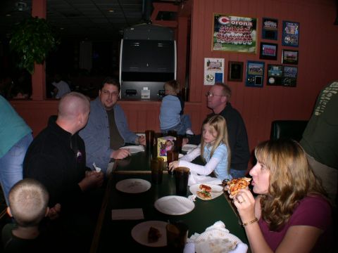 2007 Toyota FJ Cruiser - A group of people are seated at tables in a dimly lit restaurant, with some eating pizza.