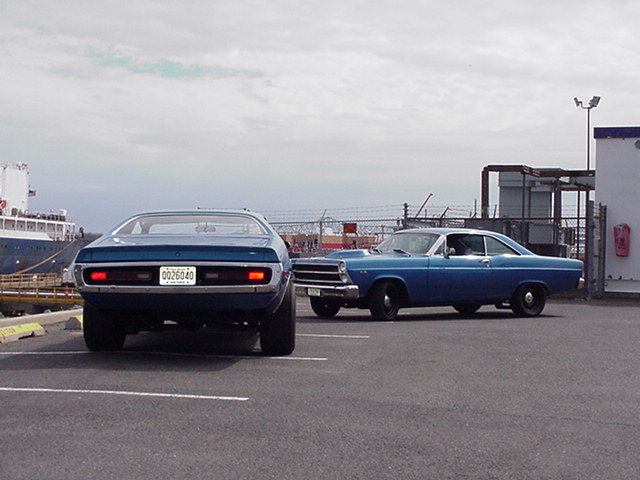 Rear view of a blue 1970s muscle car parked next to a blue 1966 Ford Fairlane