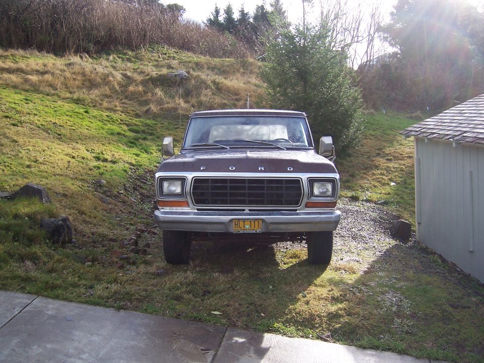 Front view of a brown Ford F-Series truck parked on a gravel driveway next to a shed