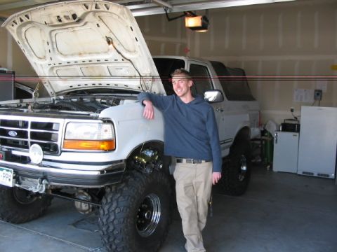 1995 Ford Bronco - A man stands next to a white Ford Bronco with its hood open in a garage.