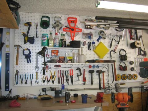 1994 Ford Bronco - A well-organized workbench displays a variety of tools hanging on a pegboard, with cleaning supplies and other items on shelves above.