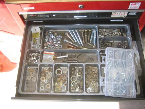 1994 Ford Bronco - A red toolbox drawer is open, revealing organized compartments filled with various nuts, bolts, and washers.