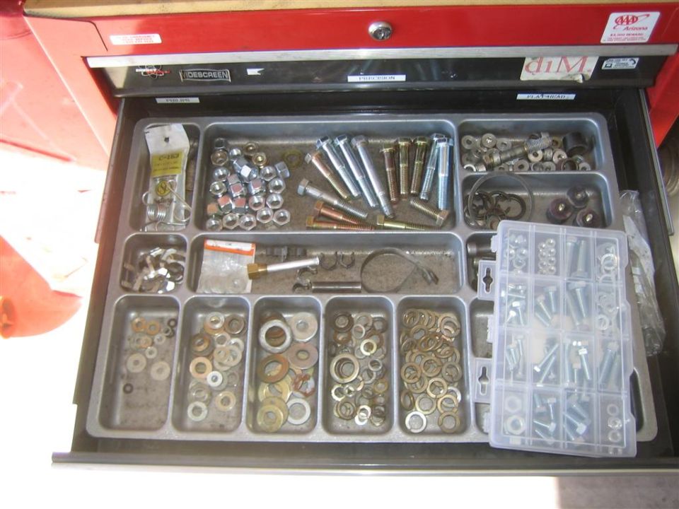 Open red toolbox drawer filled with compartments of nuts, bolts, washers, and other hardware