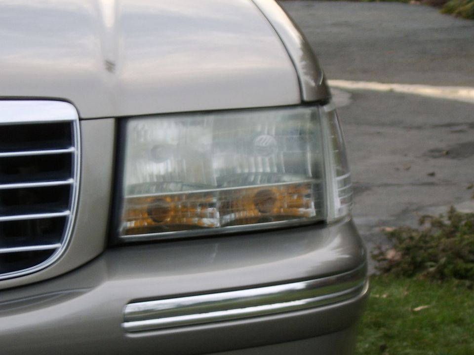 Close-up of a gold Mercury sedan headlight and grille