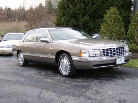 1996 Mercury Grand Marquis - A 1996 Cadillac DeVille is parked on a driveway next to another car.