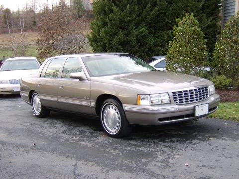 1996 Mercury Grand Marquis - A tan Cadillac sedan is parked outside with a white car in the background.