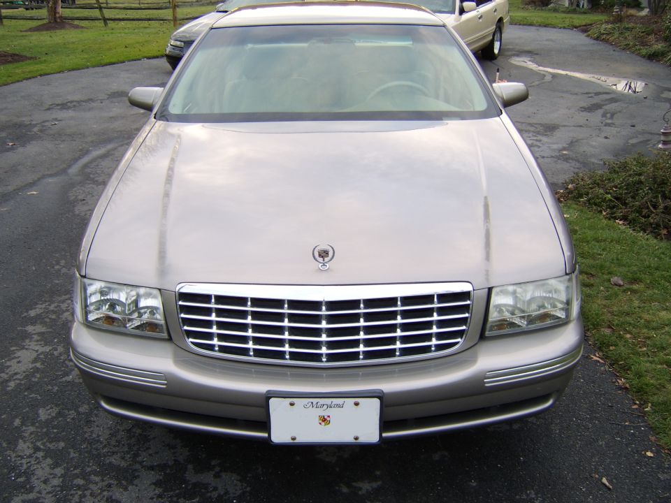 Front view of a tan Cadillac DeVille sedan with chrome grille and Maryland plate