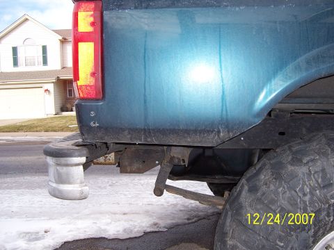 1994 Ford Bronco - Close-up of the rear of a teal SUV, showing the quarter panel, tire, and suspension components.