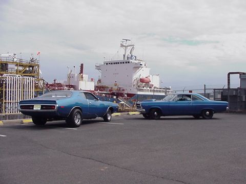 1966 Ford Fairlane - A 1971 Dodge Charger and a 1966 Ford Fairlane are parked in front of a large cargo ship.