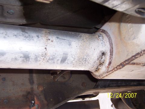 1994 Ford Bronco - Underside view of a vehicle's exhaust pipe and frame, showing rust and wear.