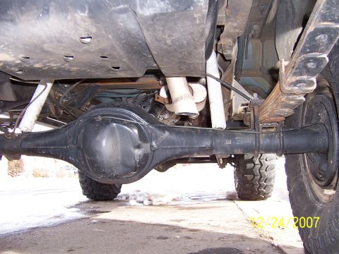1994 Ford Bronco - Underside view of a vehicle's rear axle and suspension system, with snow on the ground.