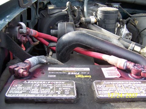 1994 Ford Bronco - Close-up of a vehicle's engine bay, focusing on the battery and wiring. Date stamp visible.
