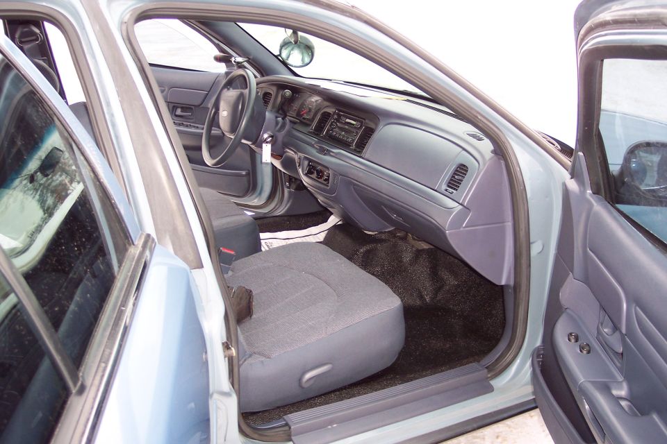 Interior of a light blue 2001 Ford Crown Victoria, showing the driver's seat, dashboard, and steering wheel