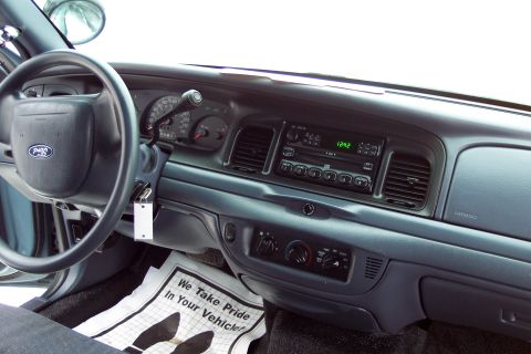 2001 Ford Crown Victoria - The interior of a 2001 Ford Crown Victoria shows the dashboard, steering wheel, and radio, with a floor mat reading 'We Take Pride In Your…