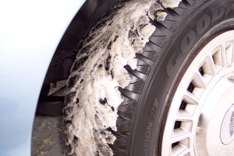 2001 Ford Crown Victoria - A close-up of a snow-covered tire and wheel on a light blue vehicle.