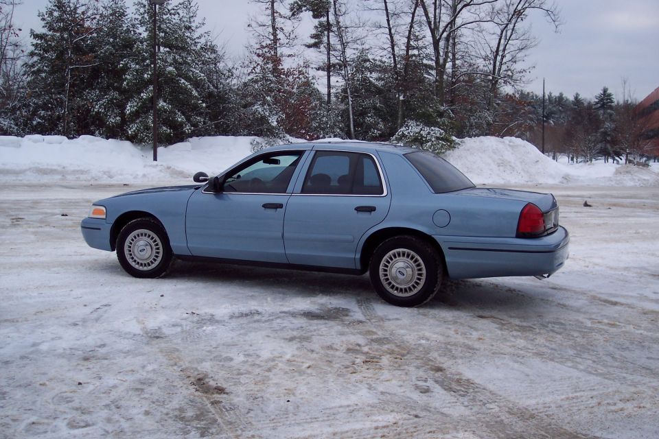 Blue 2001 Ford Crown Victoria sedan parked on a snowy lot, viewed from the rear quarter