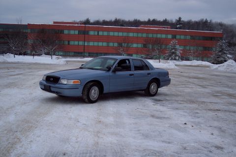 2001 Ford Crown Victoria - Blue 2001 Ford Crown Victoria parked in a snowy lot with a large red building behind it.