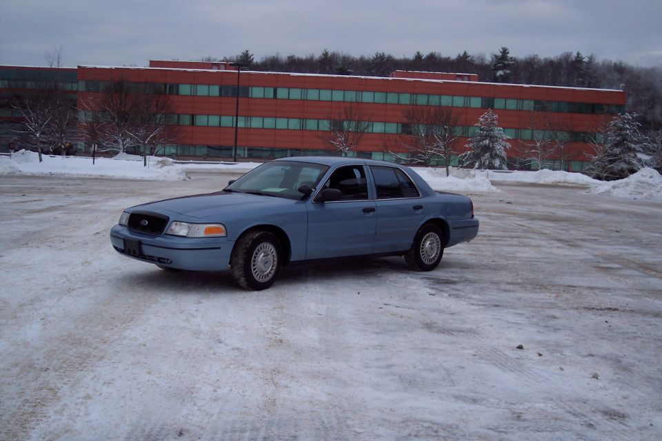 2001 Ford Crown Victoria sedan parked in snow, with a red brick building in the background