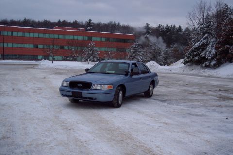 2001 Ford Crown Victoria - A blue 2001 Ford Crown Victoria sits in a snow-covered parking lot on an overcast day.