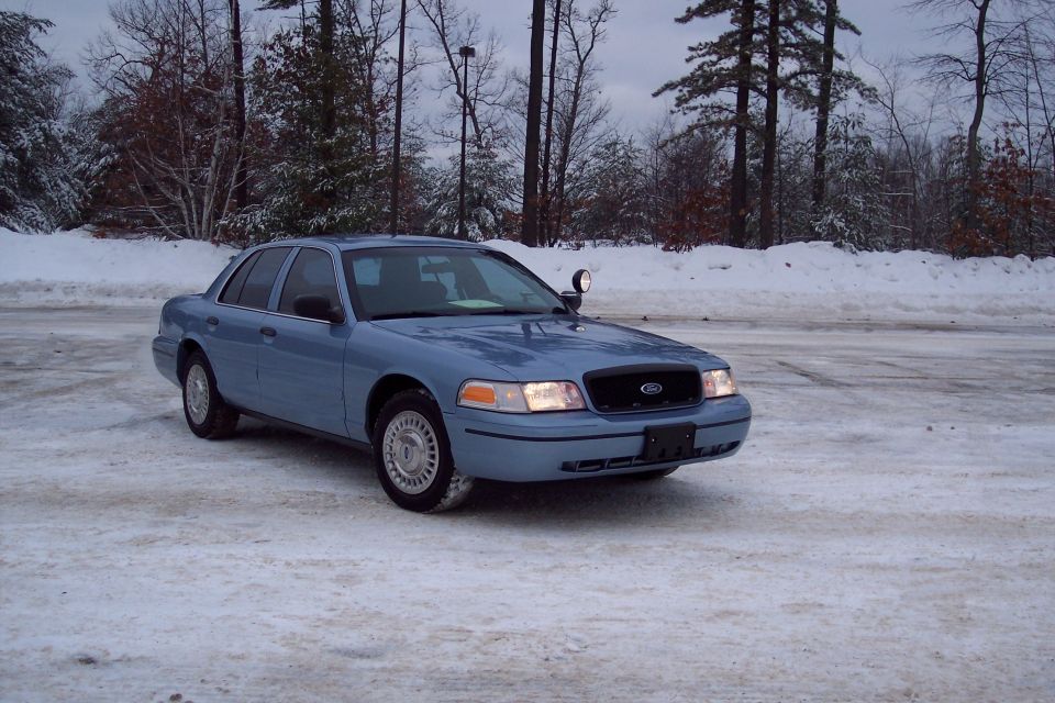 Blue 2001 Ford Crown Victoria sedan parked on a snowy surface, front 3/4 view