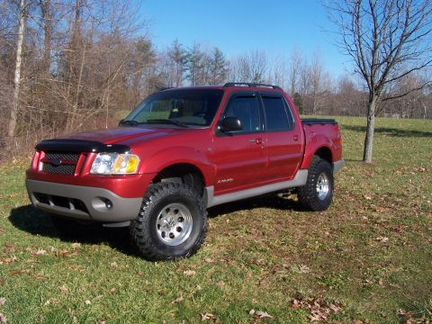 2002 Ford Sport Trac - Red 2002 Ford Sport Trac pickup truck with lifted suspension and aftermarket wheels parked outdoors.