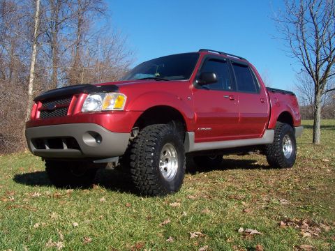 2002 Ford Sport Trac - A red 2002 Ford Sport Trac is parked on a grassy field under a clear blue sky.