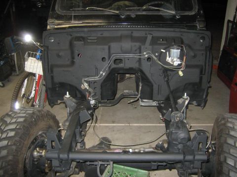 1987 Suzuki Samurai - The front chassis and firewall of a vehicle are shown, with large off-road tires attached.
