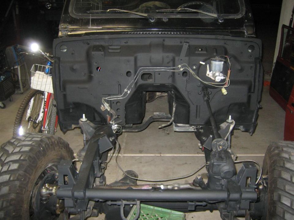 Stripped Samurai in garage with engine removed, bare firewall and front axle exposed