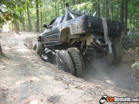 1991 Ford Bronco - Dodge Heavy Duty pickup truck with dual rear wheels is shown off-roading on a dirt trail.