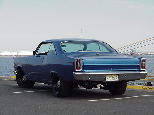 1966 Ford Fairlane coupe parked by water, rear view. License plate reads 2612-00