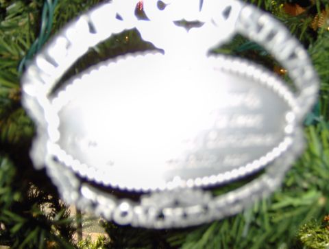 1978 Ford Bronco - A silver oval ornament with beaded trim hangs on a Christmas tree, displaying engraved text.
