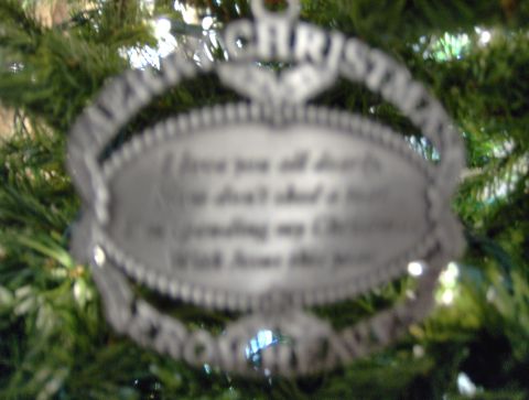 1978 Ford Bronco - A metal Christmas ornament with text is hanging on a decorated tree.