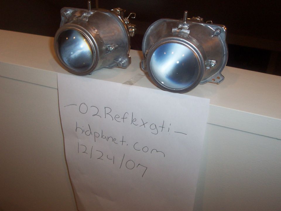 Pair of headlights with handwritten note reading "-02 Reflexgti - hidplanet.com 12/24/07"